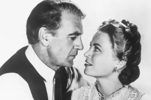 W samo południe obsada: Gary Cooper i Grace Kelly w zbliżeniu, patrzą na siebie z intensywnością.
