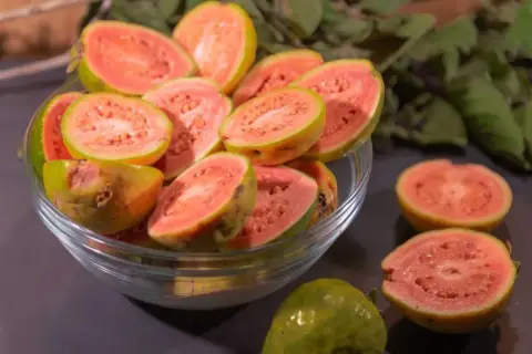 Kusząca guawa jak jeść? Pokrojone owoce w misce i na blacie, gotowe do degustacji.