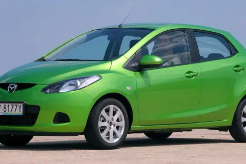 Zielona Mazda 2 DE z polskimi tablicami rejestracyjnymi WY 8177Y stoi na zewnątrz.