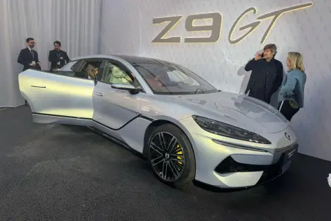 Srebrny Denza Z9 GT z otwartymi drzwiami, obok niego rozmawiają ludzie.