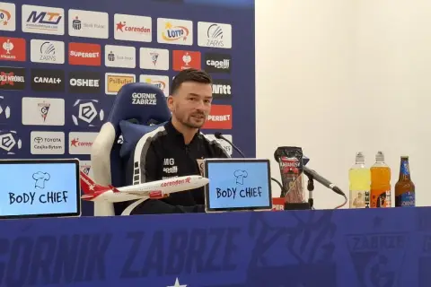 Trener Górnika Zabrze przed meczem z Rakowem Częstochowa. Na stole kabanosy, napoje i model samolotu.