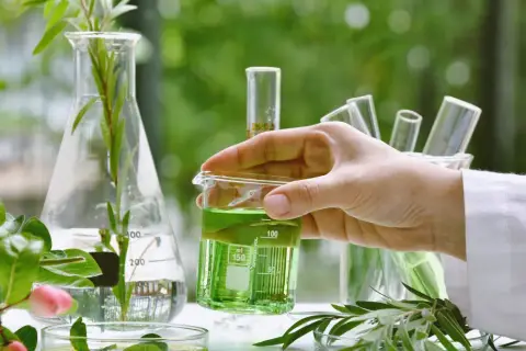 Badaczka analizuje zielony płyn w zlewce, badając naturalne składniki. To może być część procesu tworzenia produktów, o których przeczytasz w bingospa opinie.