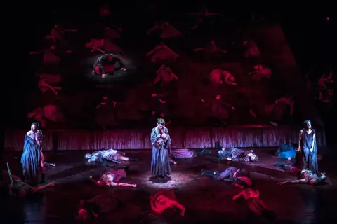 Scena z "Makbeta" w Teatrze Muzycznym Wrocław. Na scenie leżą martwi, stoi postać z dzieckiem.