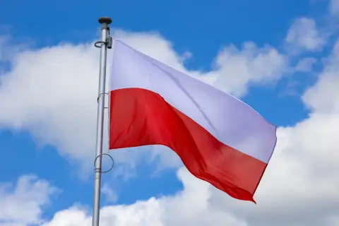 Biało-czerwona flaga Polski powiewa na tle błękitnego nieba z chmurami. Czy 2 maja jest wolny? To pytanie zadają sobie Polacy, ciesząc się świętem narodowym.