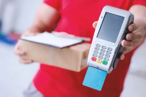Kurier z paczką i terminalem płatniczym. Płatność kartą za przesyłkę Omniva.