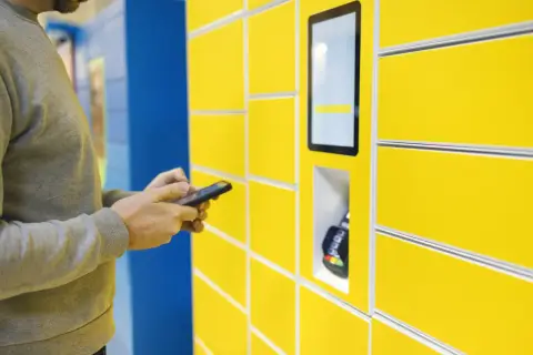 Mężczyzna używa aplikacji InPost Mobile do obsługi paczkomatu.