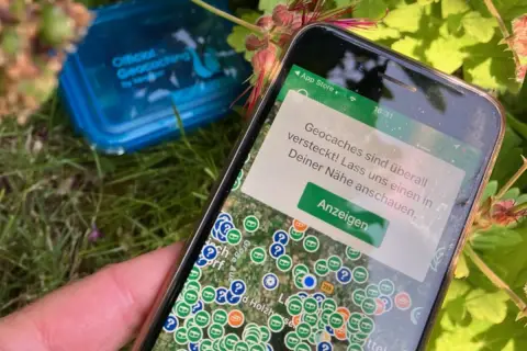 Smartfon pokazuje mapę z ukrytymi skarbami. To właśnie geocaching – zabawa w poszukiwanie skrytek z pomocą GPS.