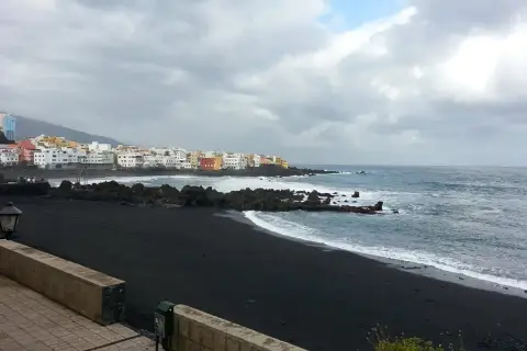 Czarna plaża i kolorowe domy na Teneryfie. Pogoda w październiku bywa zmienna, ale morze wciąż faluje.