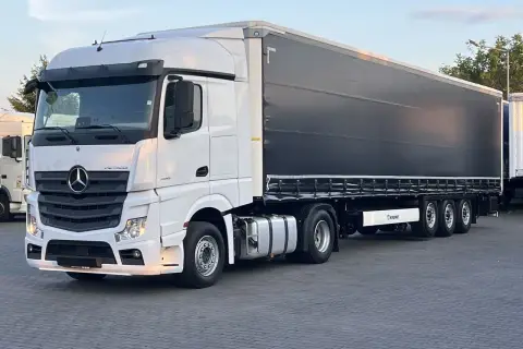 Biały Mercedes Actros MP4 z czarną plandeką naczepy Krone, gotowy do trasy.