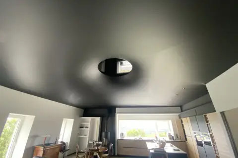 Plafond noir tendu, un cache-misère habile pour un plafond abîmé, avec une ouverture circulaire laissant apercevoir le ciel.