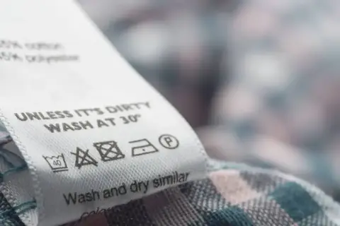 Metka z instrukcją prania: prać w 30°, nie wybielać, prasować w niskiej temperaturze. Materiał zawiera **elastan**, co zapewnia komfort noszenia.
