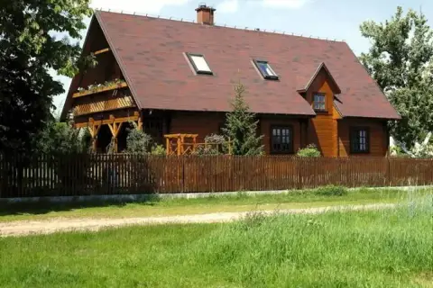Drewniana zabudowa zagrodowa, idealna dla rolników, z werandą i drewnianym płotem.