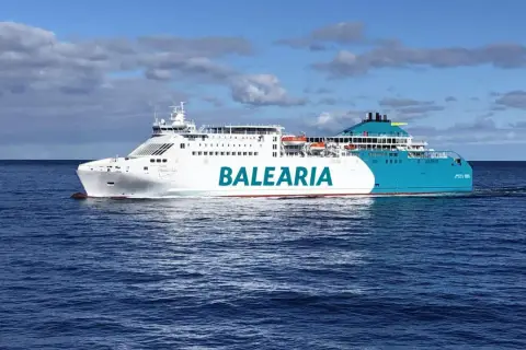 Un gran barco de Baleària navega por el mar azul, rumbo a Mallorca desde Valencia.