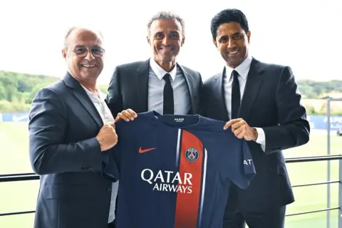 Luis Enrique, nowy trener PSG, prezentuje koszulkę klubu z prezesem i dyrektorem sportowym.