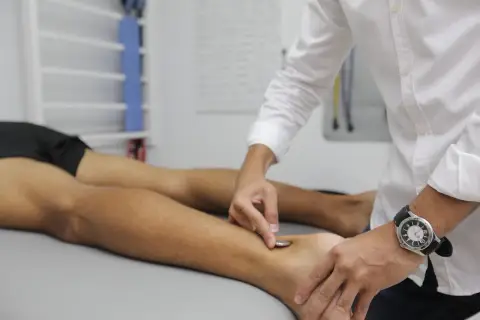 Fizjoterapeuta wykonuje zabieg na stopie pacjenta, co jest częścią rehabilitacji w ramach prewencji rentowej ZUS.