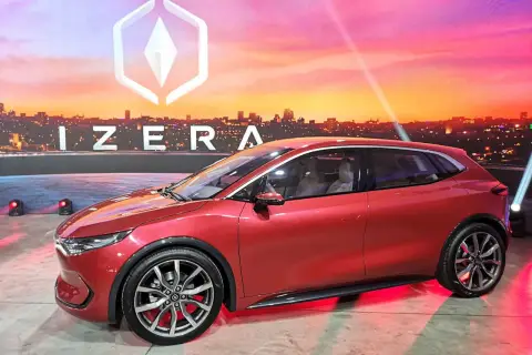 Czerwony samochód Izera na tle miejskiego krajobrazu o zachodzie słońca.