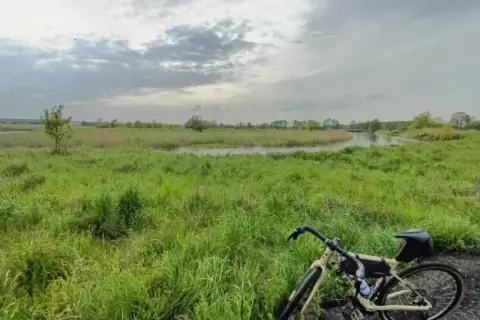 Rower na tle łąk i rzeki, gdzieś w okolicy najwyższego pasma Gór Świętokrzyskich.