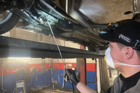 Mechanik aplikuje zabezpieczenie antykorozyjne podwozia. Sprawdź, jaka jest cena tej usługi i chroń swój samochód!