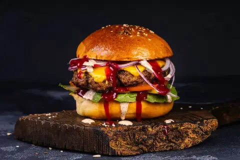 Soczysty burger wołowy z serem, cebulą i sosem. Idealny przykład, jak przyprawić mięso wołowe na burgery, by uzyskać wyśmienity smak.