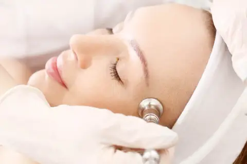Zabieg oxybrazji na twarz. Kosmetolog w rękawiczce wykonuje delikatny peeling skóry.