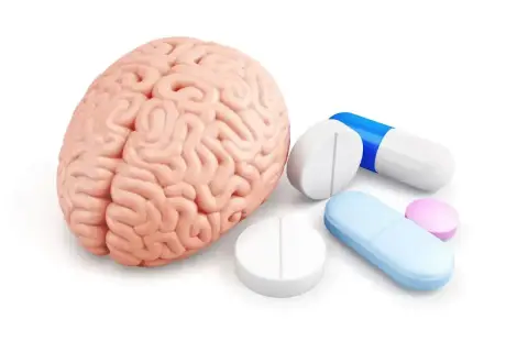Model ludzkiego mózgu obok tabletek i kapsułek, sugerujące leczenie psychotropowe.