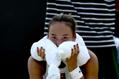 Zmęczona zawodniczka zheng tennis wyciera twarz ręcznikiem.