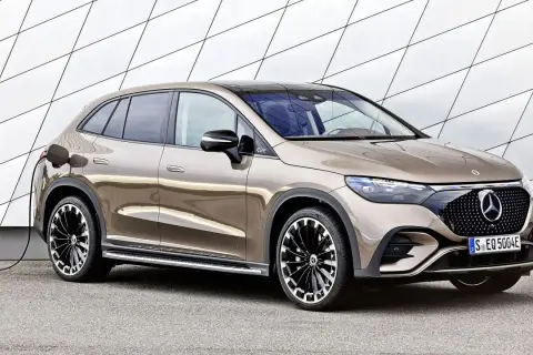 Brązowy Mercedes EQC na ładowaniu przy nowoczesnej ścianie. Stylowy SUV z elektrycznym napędem gotowy do drogi.
