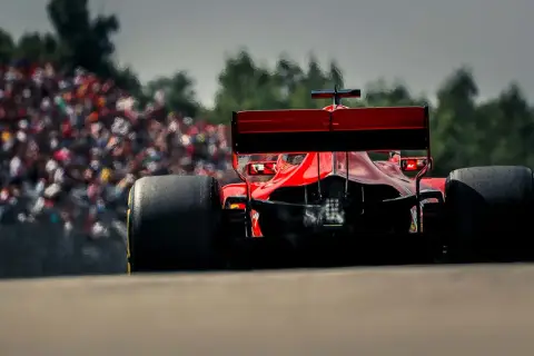 Ein roter Formel 1 Bolide rast auf die Tribüne zu. Man fragt sich, wie viel PS ein Formel 1 Auto hat, wenn es so schnell ist.
