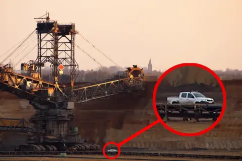 Gigantyczna koparka, największa koparka na świecie, w kopalni odkrywkowej. W powiększeniu widać mały biały pickup.