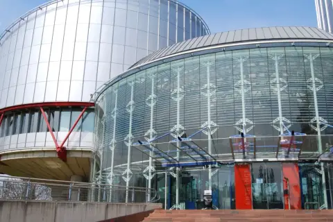 Nowoczesny budynek z przeszklonym wejściem i metalową fasadą. Tu zapadają ważne decyzje, tworząc precedens dla przyszłych pokoleń.