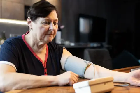 Kobieta w średnim wieku mierzy ciśnienie. Dba o prawidłowe ciśnienie tętnicze u 50-latka, monitorując je w domu.