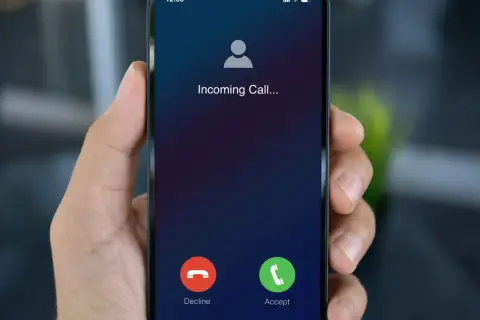 Dłoń trzyma smartfon z ekranem "Incoming Call...". Dowiedz się, jak dzwonić przez internet za darmo, by zawsze być w kontakcie.