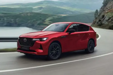 Czerwona Mazda CX-60 3.3 diesel pokonuje zakręt na malowniczej drodze.