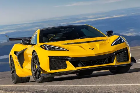 Żółty Chevrolet Corvette C7 ZR1 z dużym tylnym skrzydłem pędzi po górskiej drodze, gotowy na każde wyzwanie.