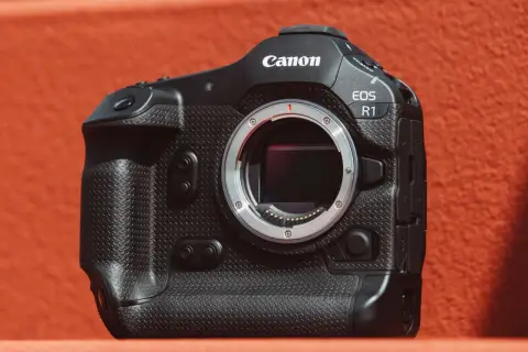 Profesjonalny aparat Canon EOS R1 z obiektywem na pomarańczowym tle.