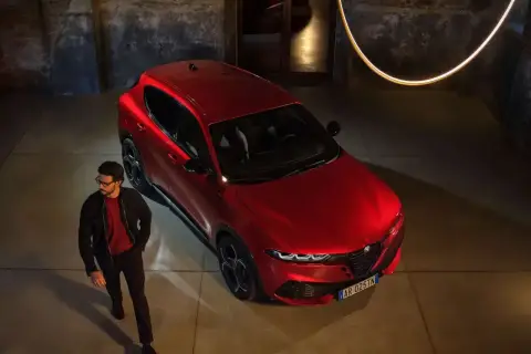 Elegancki mężczyzna obok czerwonego Alfa Romeo Tonale. Sprawdź aktualną alfa romeo tonale cena i odkryj jego styl.