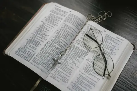 Otwarta Biblia, krzyż na łańcuszku i okulary. Może to symbolizować św. Brygidę, jej modlitwę i 12-letnie objawienia.