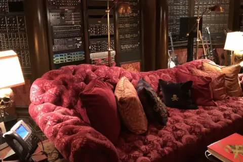 Luxuriöses rotes Samtsofa im Hans Zimmer Studio, umgeben von Musik-Equipment und Gitarren.