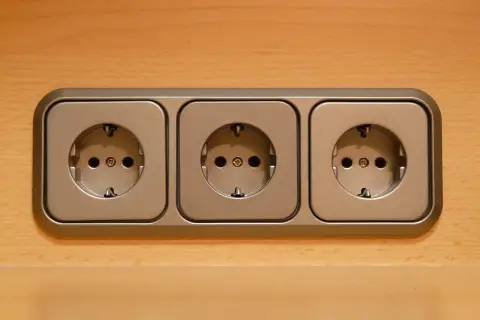 Trzy gniazdka elektryczne na drewnianym tle. Nagle nastąpiło odłączenie prądu bez powiadomienia, pozostawiając je bezużytecznymi.