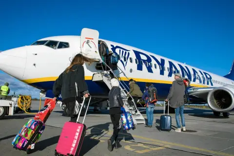 Odprawa Ryanair: pasażerowie z walizkami wchodzą po schodkach do samolotu.