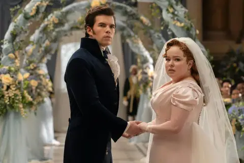 Para młoda, Colin i Penelope, trzymają się za ręce podczas ceremonii. Bridgertonowie sezon 3.