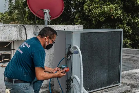 Technik sprawdza czujnik ciśnienia klimatyzacji za pomocą manometru.