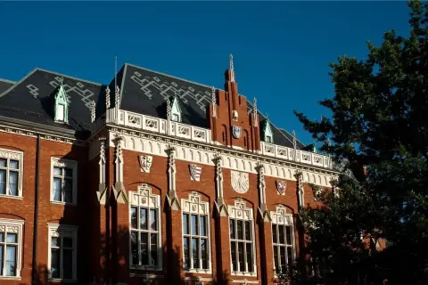 Elegancka fasada jednego z uniwersytetów w Krakowie, z charakterystycznymi detalami architektonicznymi i herbami.