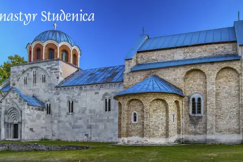 Kamienne mury i niebieskie dachy monastyru Studenica wznoszą się na tle zielonych wzgórz.