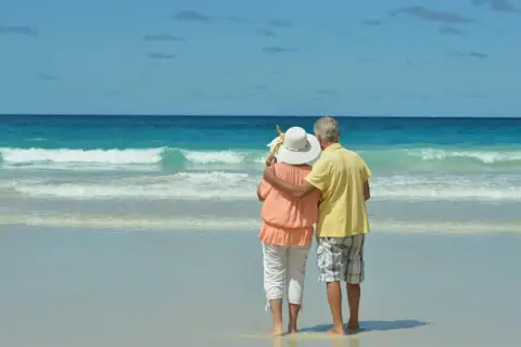 Pareja mayor disfrutando de sus viajes El Corte Inglés mayores 60 años en una playa paradisíaca.