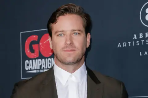 Armie Hammer, med sina blå ögon och mörk kostym, poserar framför en bakgrund med texten "GO CAMPAIGN".