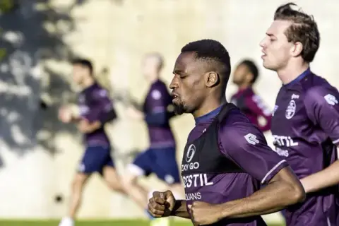 Fußballer im Trainingsanzug machen einen Shuffle Run auf dem Feld.