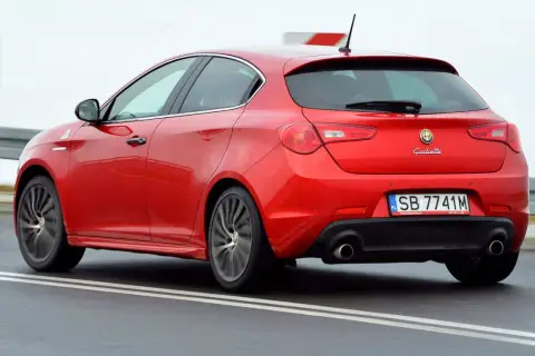 Czerwona Alfa Romeo Giulietta w ruchu. Wiele osób szuka alfa romeo giulietta opinie, by poznać wrażenia z jazdy tym modelem.