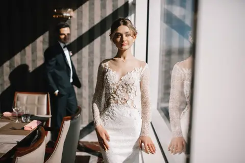 Elegancka suknia ślubna z koronkową górą i długimi rękawami, idealna dla niskiej osoby, która chce wyglądać zjawiskowo.