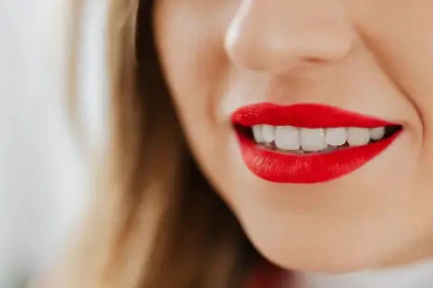 Labios rojos vibrantes y una sonrisa deslumbrante.
